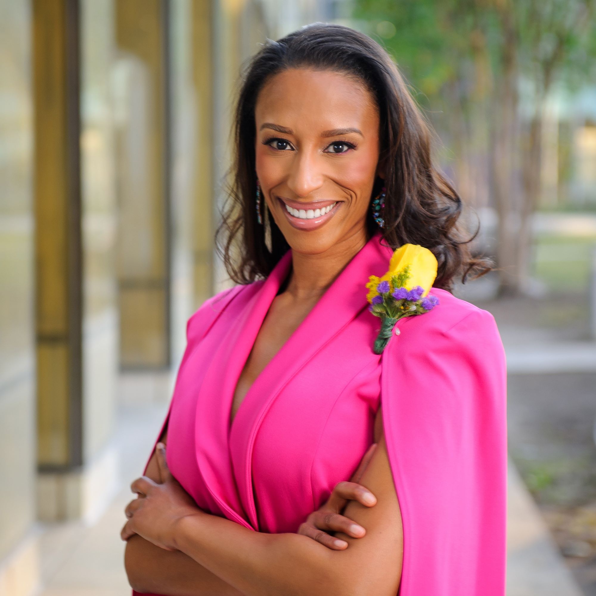 Whitney Breaux in a pink suit with her arms crossed 