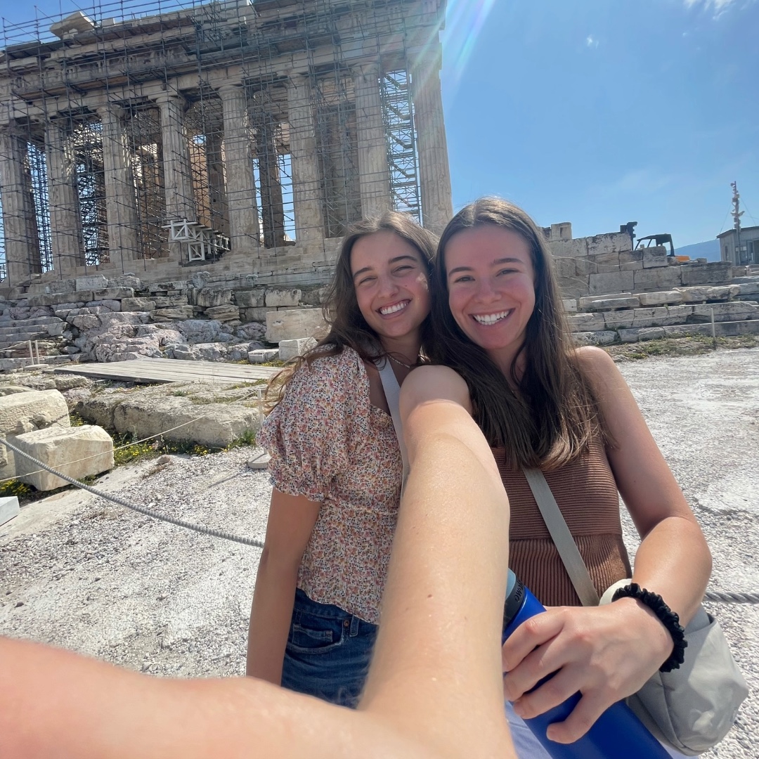 A photo of two LSU Ogden Honors College students taking a selfie in front of ancient ruins in Italy.