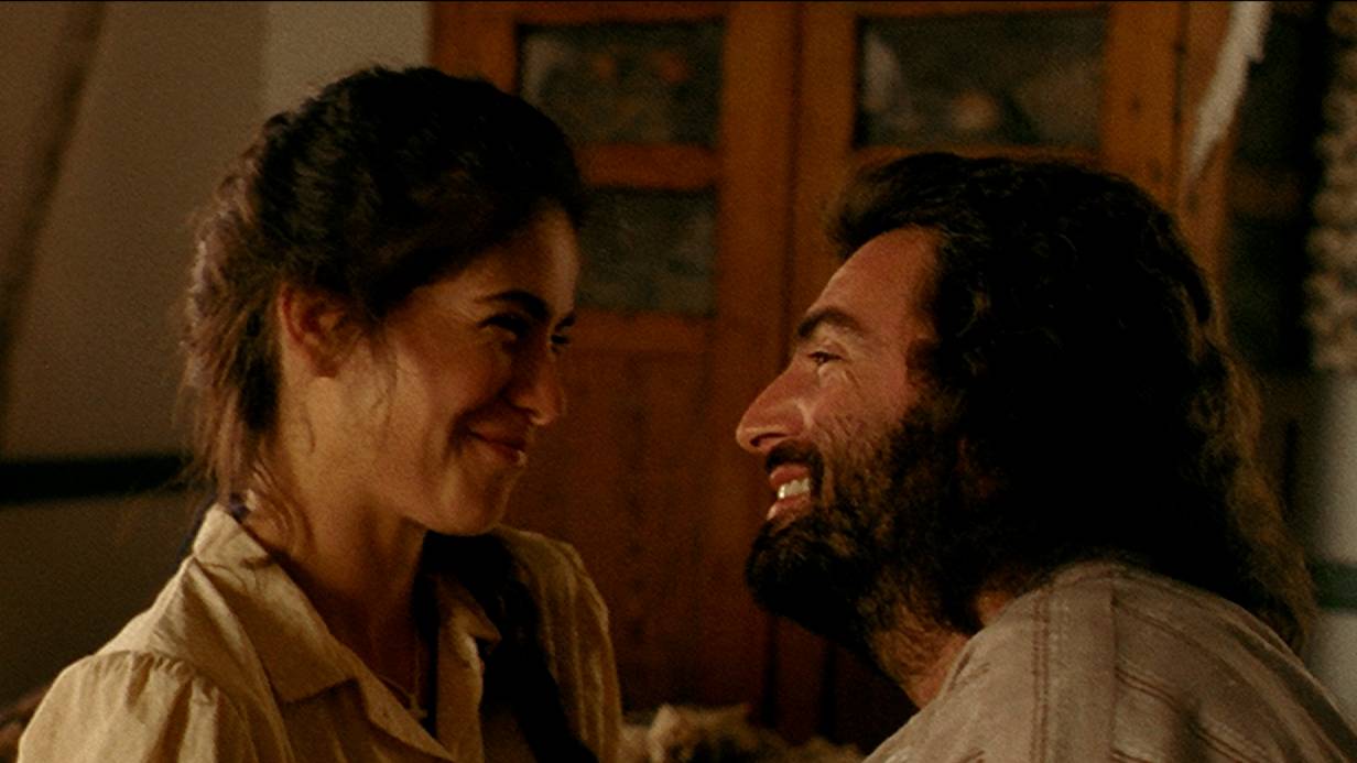 A still image from the movie Belizaire the Cajun. Belizaire and Alida look at eachother tenderly.